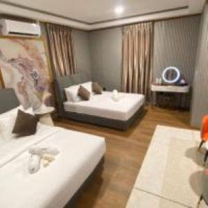 A comfortable double bedroom at Blue Ocean Resort in the archipelago featuring two large beds, a modern style vanity with a lit mirror, solid wood floors, and air con.