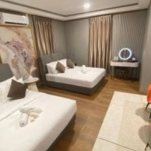 A comfortable double bedroom at Blue Ocean Resort in the archipelago featuring two large beds, a modern style vanity with a lit mirror, solid wood floors, and air con.