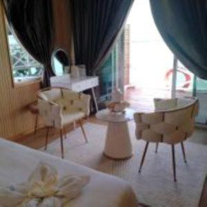 A cozy family room at Blue Ocean Resort on the Celebes Sea featuring modern chairs, floor to ceiling glass doors, traditional style wooden walls with polished wood floors, and air con.