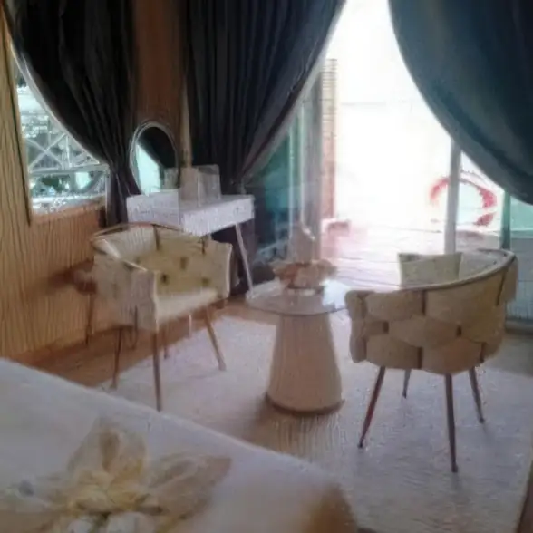 A cozy family room at Blue Ocean Resort on the Celebes Sea featuring modern chairs, floor to ceiling glass doors, traditional style wooden walls with polished wood floors, and air con.