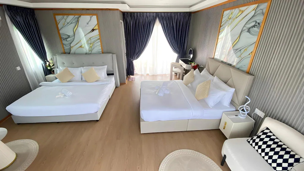 A bright family bedroom at Blue Ocean Resort over the Celebes Sea featuring two large beds, modern style orange chairs, a vanity desk, elegant hardwood floors, and air con.