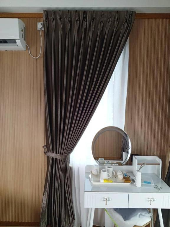 A sleek bedroom vanity space at Blue Ocean Resort near Pulau Bum Bum featuring a modern white desk, lighted mirror, traditional style wood panel walls with rustic timber floors, and A/C.